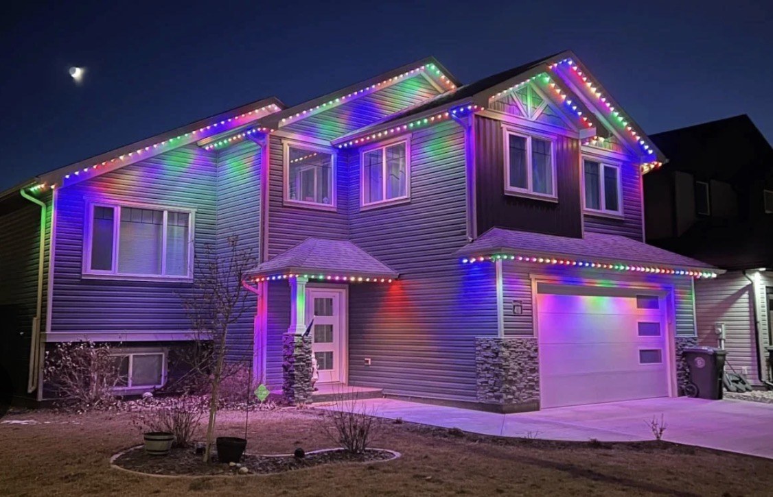 Two-story house with rainbow discrete puck lights on the roofline