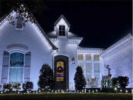 White house with cool white soffit puck lights and reindeer decor